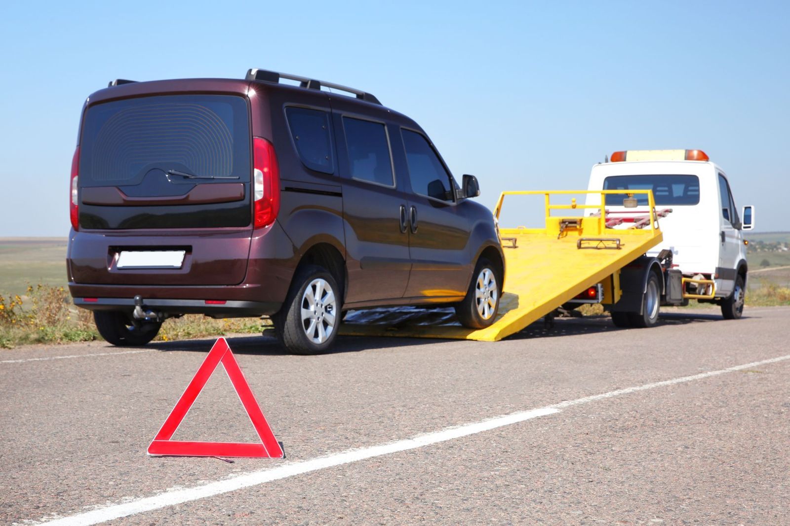 Carroattrezzi di Accurso Group che carica un veicolo in panne, con il triangolo di emergenza in strada