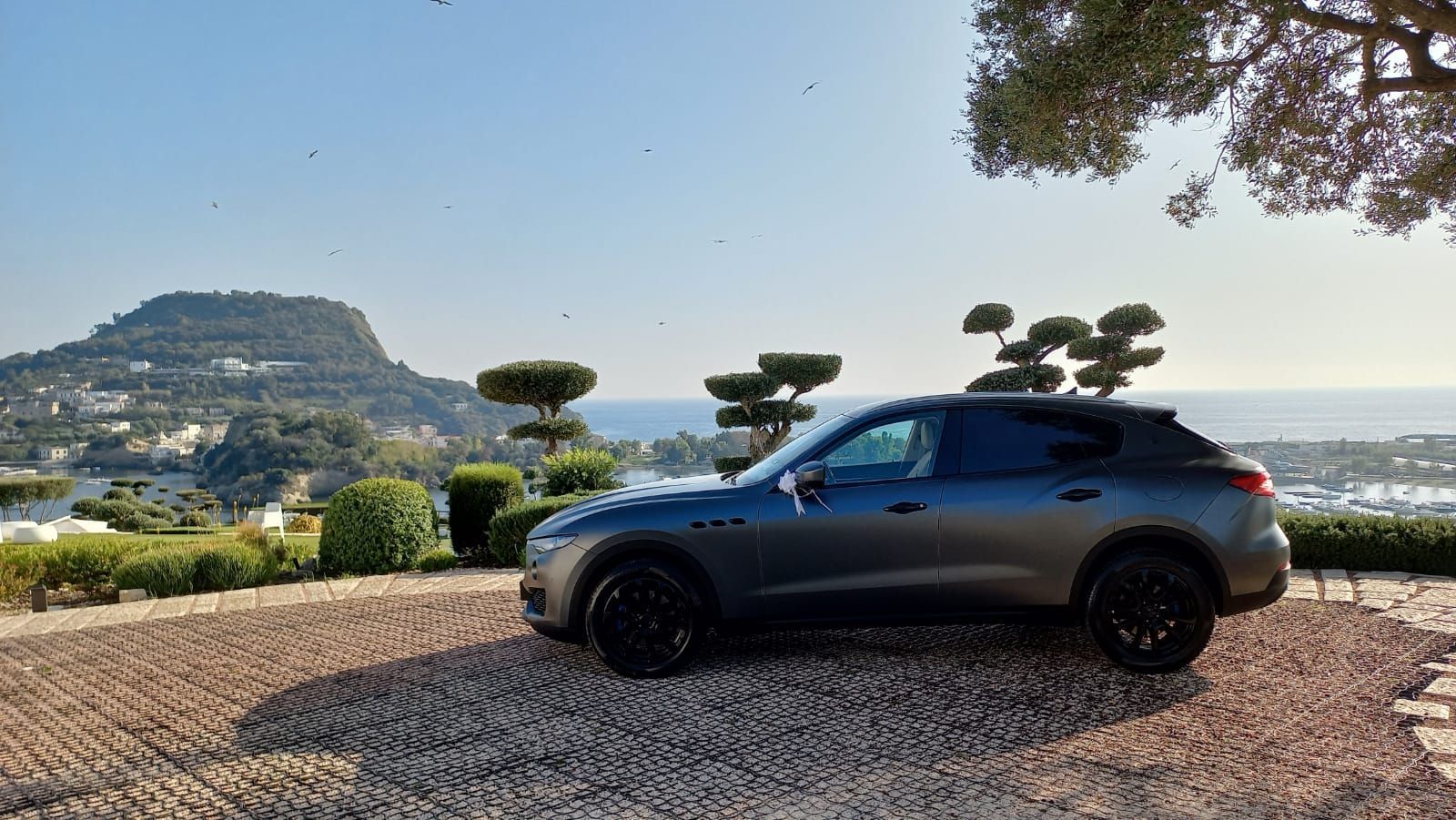 Maserati grigia vista di profilo con il mare sullo sfondo