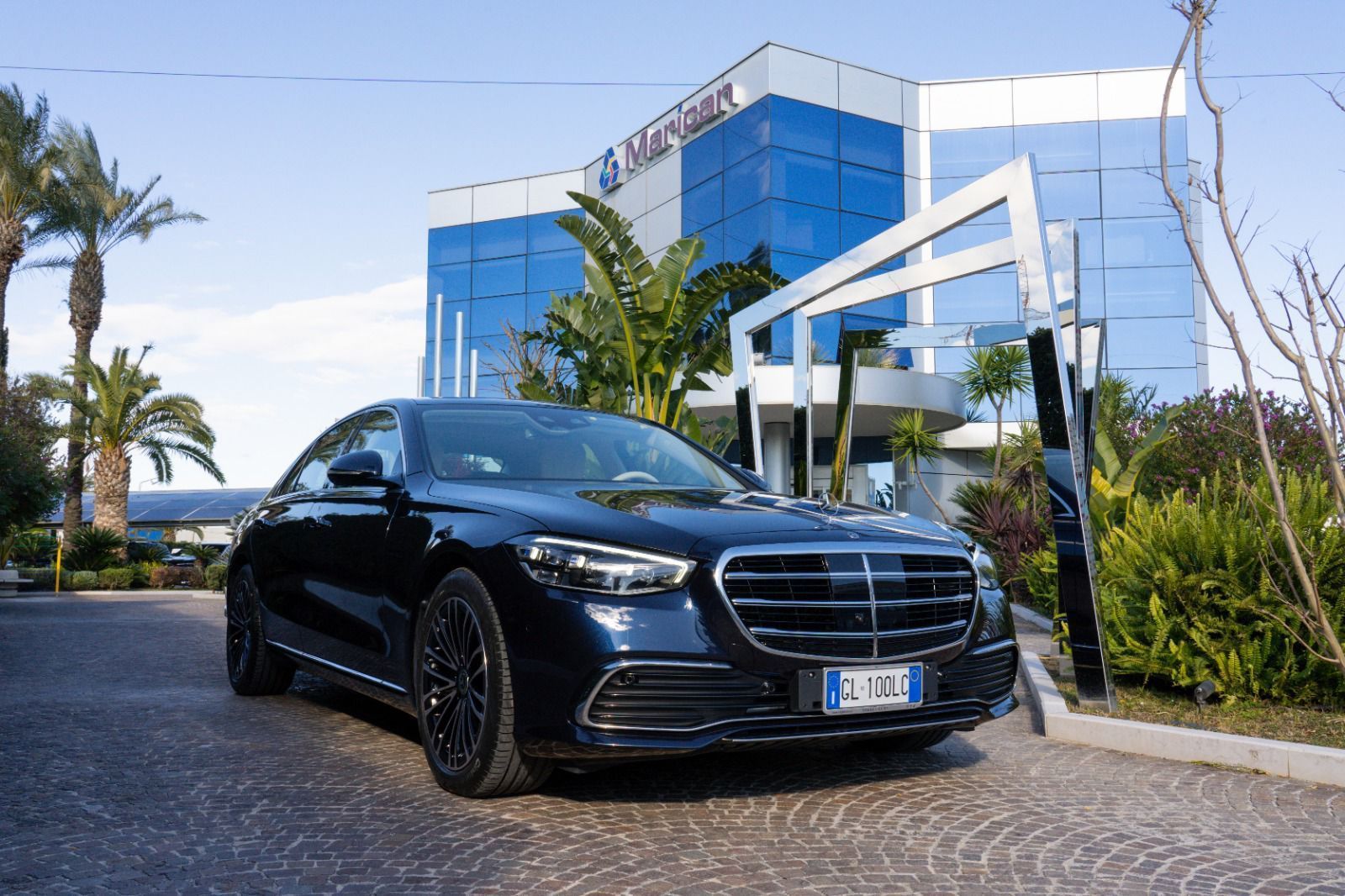Mercedes Classe S blu davanti a un hotel con palme